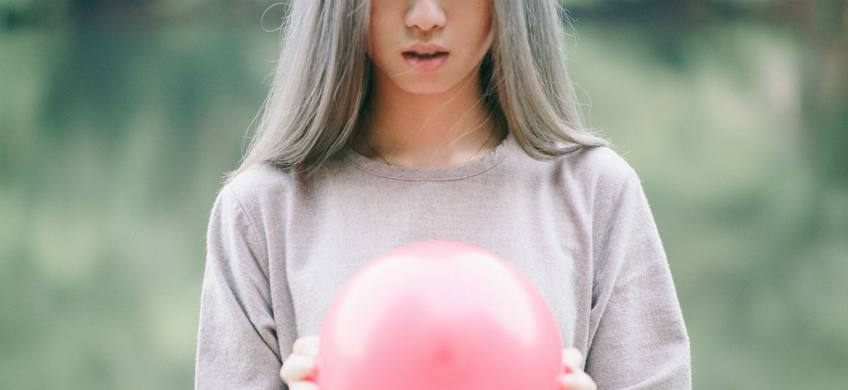 woman with silver hair holding pink balloon